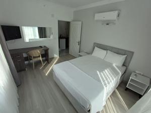 ein Schlafzimmer mit einem weißen Bett, einem Tisch und einem Schreibtisch in der Unterkunft Aykaç Hotel in Silifke + 14 Fotos
