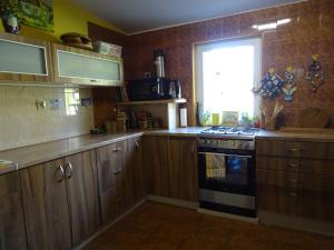 a kitchen with wooden cabinets and a stove and a window at Zakątek Transformacji in Łużna
