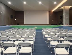 an empty room with white chairs and a screen at Sungsan Marina Hotel in Seogwipo