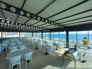 ein Raum mit Tischen und Stühlen und dem Meer in der Unterkunft Aykaç Hotel in Silifke