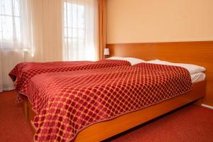 a bedroom with a bed with a red and white checkered blanket at Hotel Dominika in Bratislava +37 photos
