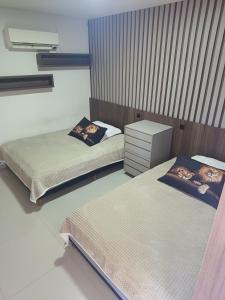 a bedroom with two beds and a dresser in it at Pousada Mineiro in Curitiba