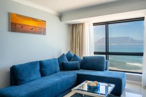 a blue couch in a living room with a large window at Blaauwberg Beach Hotel in Bloubergstrand