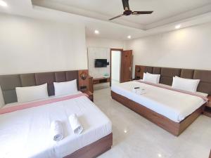 a bedroom with two beds and a television at Hotel Gurukripa in Ujjain