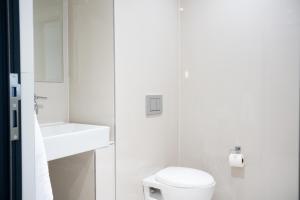 a white bathroom with a toilet and a sink at Blaauwberg Beach Hotel in Bloubergstrand