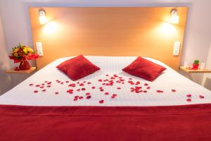 a bed with red roses on it with two pillows at Carré Py' Hôtel in Bagnères-de-Bigorre