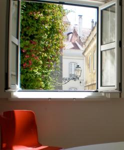 une fenêtre ouverte avec une chaise rouge donnant sur l'extérieur dans l'établissement Terrace Principe Real, à Lisbonne