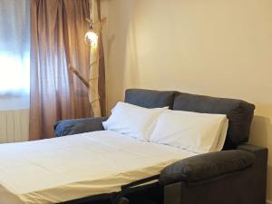 a bed in a room with a couch and a window at Apartamento Cumbre Loba in La Pinilla