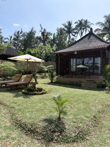 a house with chairs and an umbrella in a yard at Wana Ayu Jelijih Villas by Dhananjaya Hospitality in Tampaksiring +14 photos