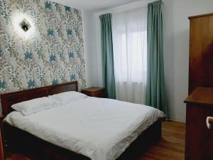 a bedroom with a bed and a window with green curtains at Vila Esperia Rânca in Ranca
