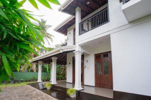 a white house with a wooden door at Villa Amora Hikkaduwa in Hikkaduwa