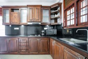 a kitchen with wooden cabinets and black counter tops at Villa Amora Hikkaduwa in Hikkaduwa