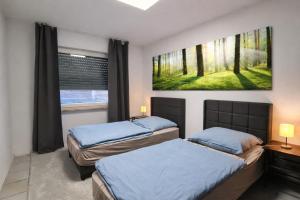 two beds in a bedroom with a painting on the wall at Gästehaus Ferienwohnung Wohnung#3 Jülich in Jülich