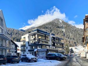 a building with cars parked in front of a mountain at Appartement Chesa Monte in Ischgl