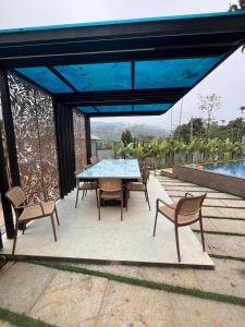 a patio with a table and chairs and a blue umbrella at Bumblebee Pool Villa Munnar in Anachal