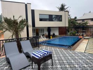 a swimming pool with two chairs and a house at Bumblebee Pool Villa Munnar in Anachal