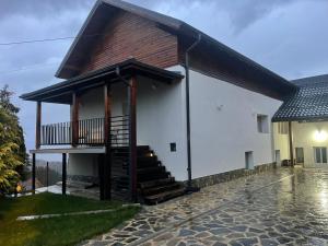 a white house with a staircase on the side of it at Wildglowlodge in Petroşani