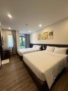 a hotel room with two beds and a desk at Nhã Hotel A in Thôn Mỹ Phước