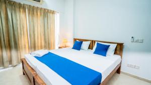 a bedroom with a large bed with blue and white pillows at Crystal Sand Mount Lavinia in Mount Lavinia