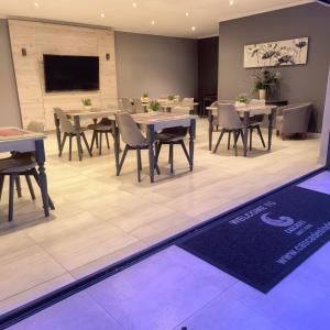 a dining room with tables and chairs and a tv at Cascades Guest Lodge in Nelspruit