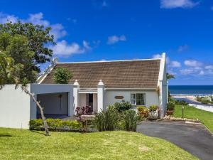 a white house with the ocean in the background at The Estuary Country Estate, Villa "Once Upon A Tide" in Port Edward