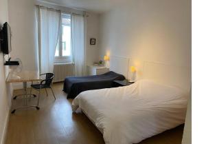 a bedroom with two beds and a desk and a television at Hôtel Brasserie Le Lion d'Or in Meximieux