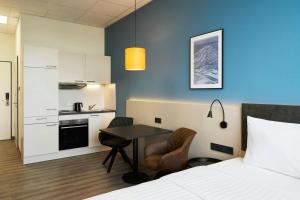 a bedroom with a bed and a table and a kitchen at Four Points Flex by Sheraton Östringen in Östringen