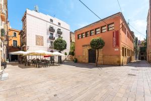 an empty street with tables and umbrellas and buildings at FORUM EXPERIENCE Adults Only in Tarragona