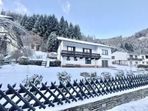 a house with a fence in the snow at Forestside Raceway Hideaway in Oberweg