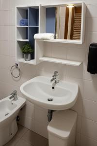 a white bathroom with a sink and a toilet at Baita Brunate Cao in Brunate