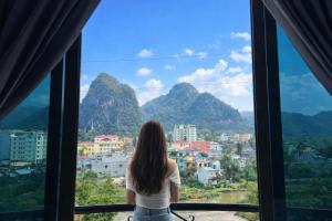 a woman looking out a window at the mountains at Kiên Bin Đồng Văn Hotel in Dồng Văn