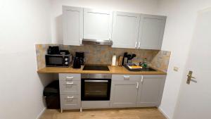 a kitchen with white cabinets and a sink and a microwave at Bitterfeld Apartment modern & gemütlich in Holzweißig +4 photos