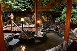 a pool of water with a wooden walkway in a garden at Ito Kowakien in Ito