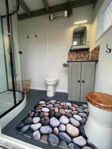a bathroom with a toilet and a rock floor at Op zoek naar een leuke overnachting Te huur Prachtig Tiny House De Hutte in Siddeburen