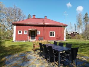 a table and chairs in front of a red barn at Villa Metsänvartija in Vihtijärvi