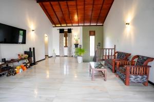 a living room with a couch and chairs and a tv at Villa Amora Hikkaduwa in Hikkaduwa