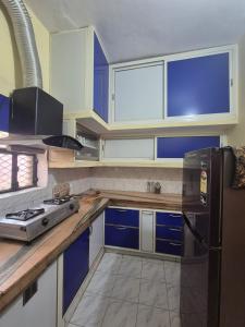 a kitchen with blue and white cabinets and a refrigerator at Triveni Bliss in Prayagraj