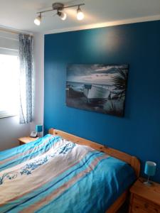 a bedroom with a bed with a blue wall at Haus Deichblick in Dornum