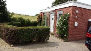 a red brick house with a window and bushes at Haus Deichblick in Dornum