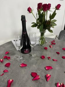 a table with roses and a bottle of wine and glasses at LuxRooms - rooms with private jacuzzi in Bjelovar