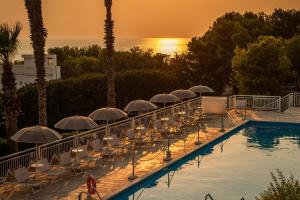 a row of tables and chairs with umbrellas next to a pool at Grand Hotel Riviera - CDSHotels in Santa Maria al Bagno