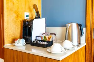 a counter with a coffee maker and cups on it at Blaauwberg Beach Hotel in Bloubergstrand
