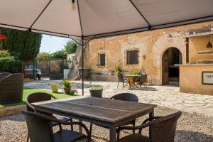 a patio with a wooden table and chairs under an umbrella at AT504 Rustic house with private pool in Roda de Bará