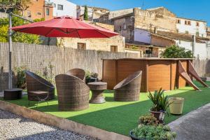 a patio with chairs and an umbrella and grass at AT504 Rustic house with private pool in Roda de Bará
