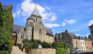 a large stone church with a tower on a street at La Pierre du Bonheur in Saint-Denis-dʼAnjou