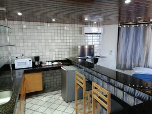 a kitchen with a counter with two wooden chairs at Pousada Trip Inn Recife in Recife