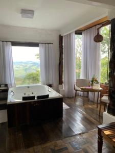 a bath tub in a room with a large window at Suítes Ad`vinho in Lavras Novas +72 photos