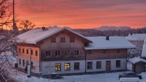 a wooden house with snow on the roof at sunset at Kaffeekandl Café & Pension in Glonn