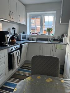 a kitchen with white cabinets and a sink and a table at Windsor Gate Room,Windsor in Dorney +13 photos