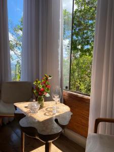 a table with two wine glasses and a window at Suítes Ad`vinho in Lavras Novas